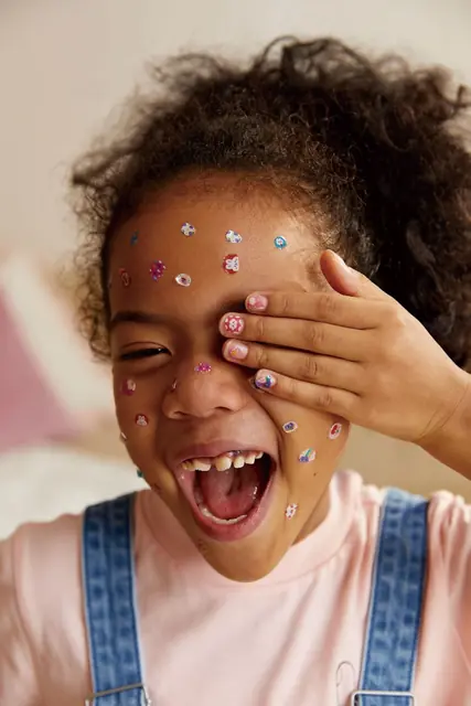 A laughing child with mideer face stickers