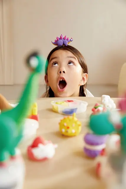 A surprised child with a mideer dinosaur toy